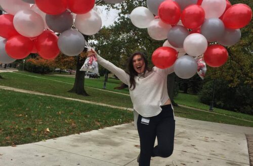 girl holding scarlet, gray and white balloons