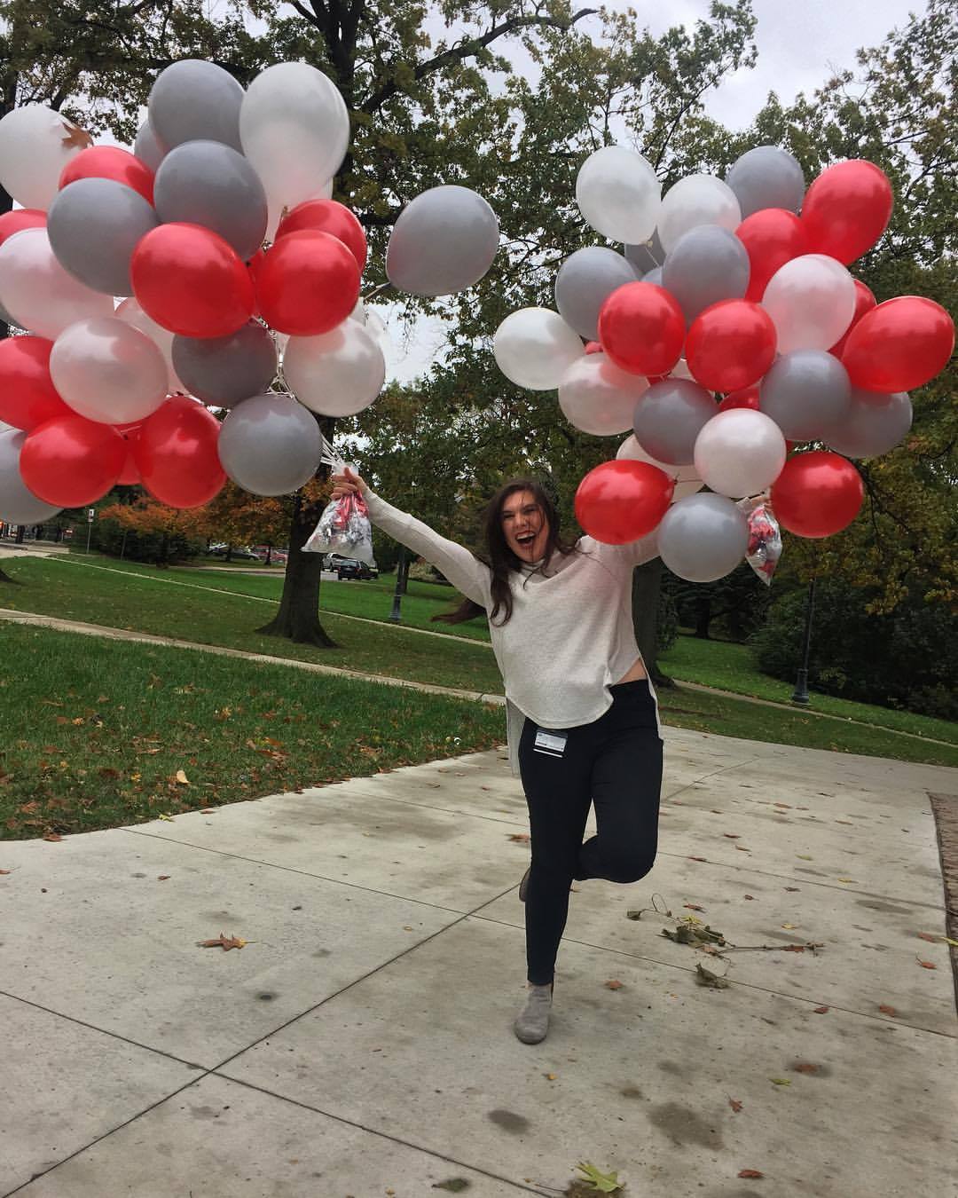 girl holding scarlet, gray and white balloons